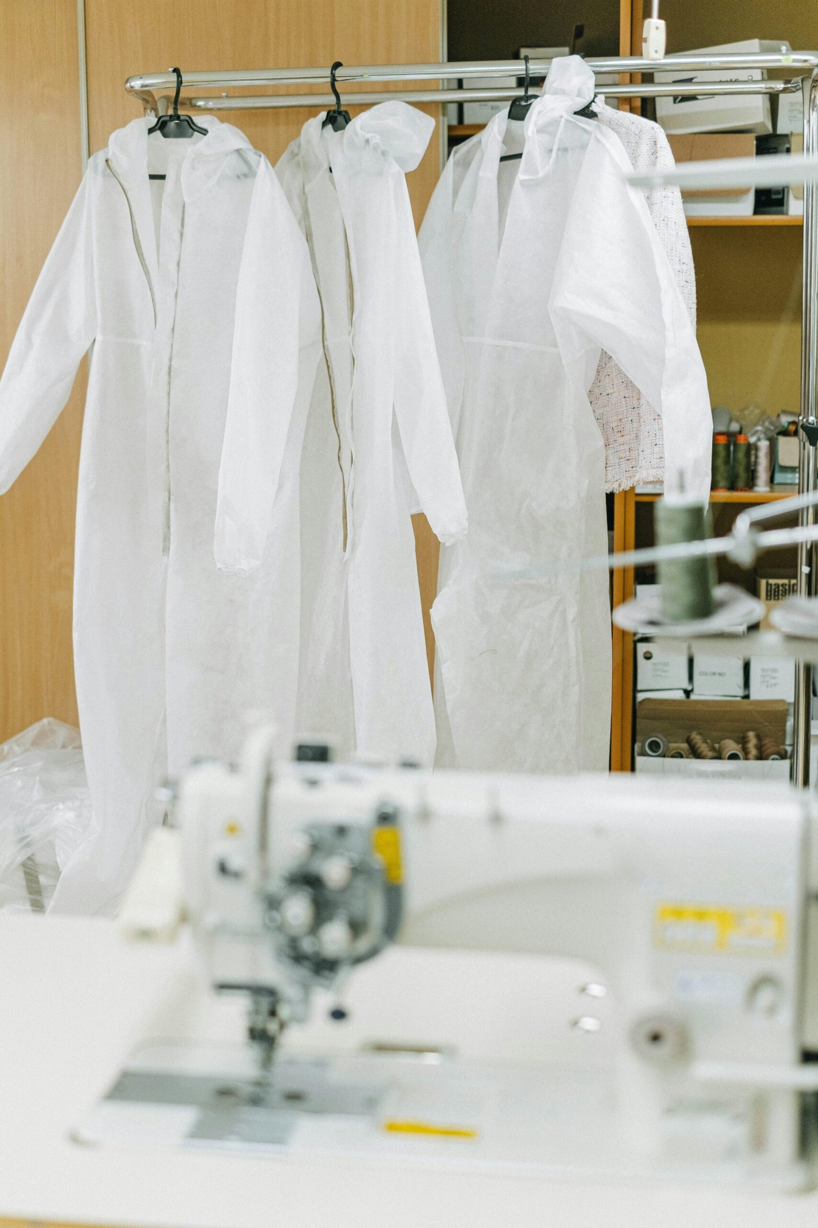 A sewing room showcasing hanging protective suits and a sewing machine.